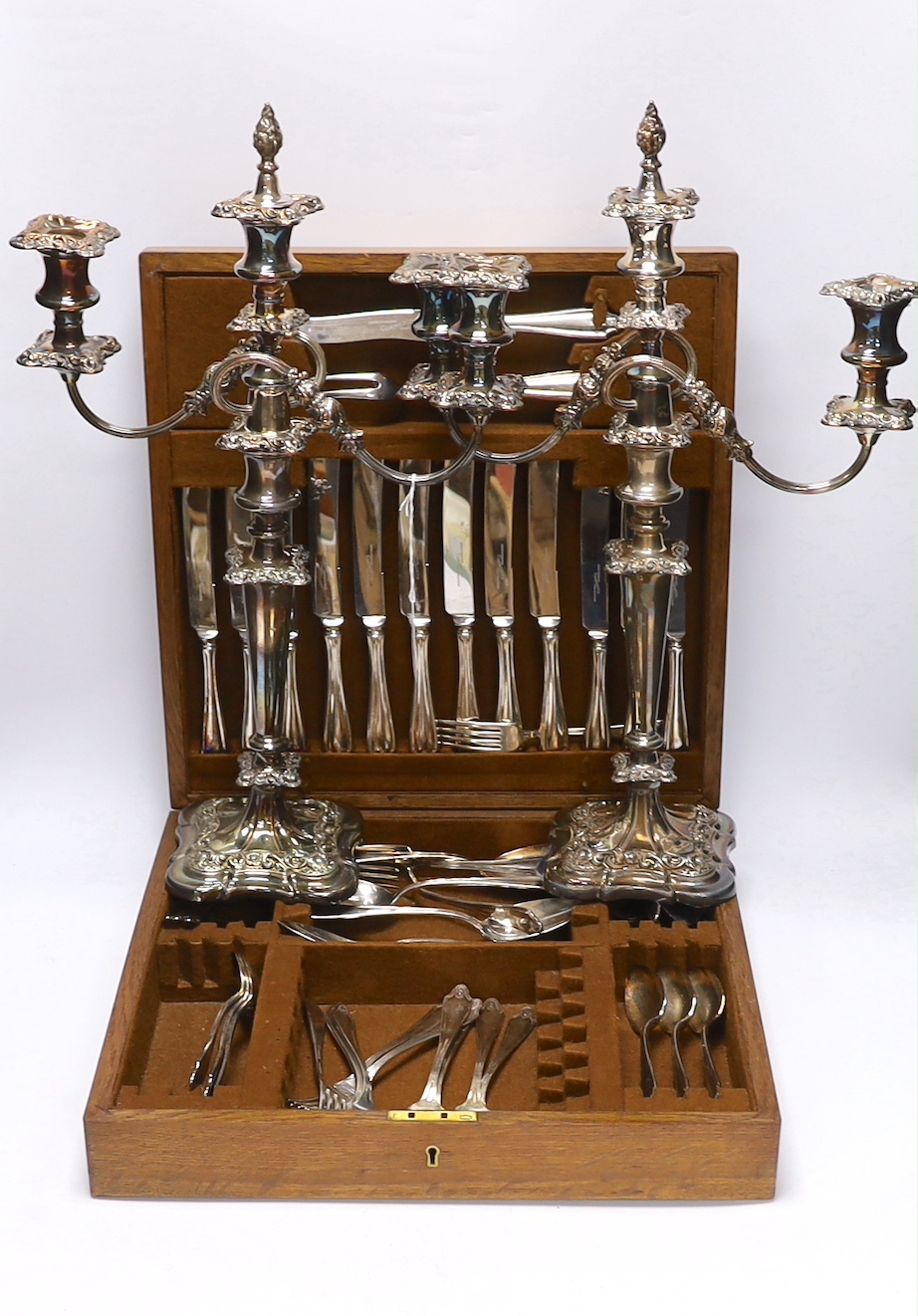 An oak cased canteen containing Sheffield ‘Super stainless’ flatware and a pair of plated candelabra, 46cm